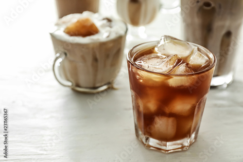 Glass with cold coffee on white table