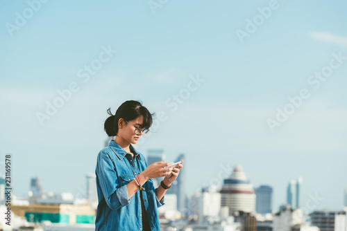 Asian woman used smart phone reads and text message on her smart phone in the city scene background with copy space