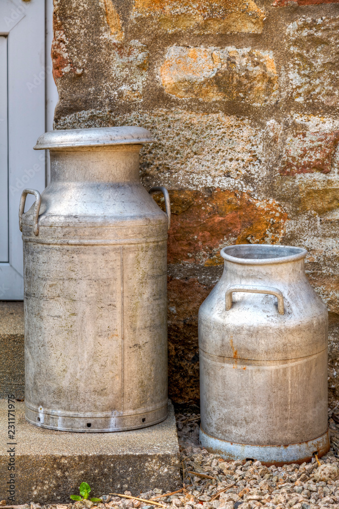 Two traditional milk churns on a door step Two traditional milk churns on a door step