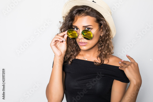 Photos Cheerful curly girl in sunglasses and straw hat laughing on white background