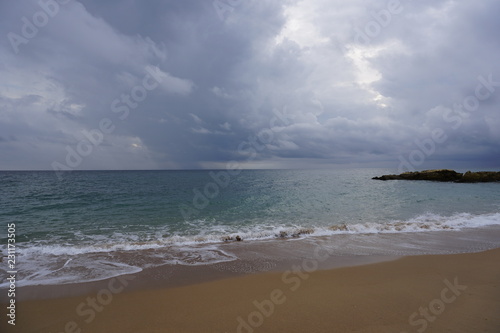 Rain clouds over the ocean. Surf waves and sandy beach