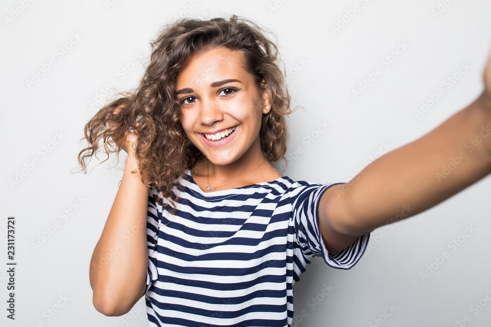 Close up portrait of a happy young curly woman making selfie against isolated white background Close up portrait of a happy young curly woman making selfie against isolated white background