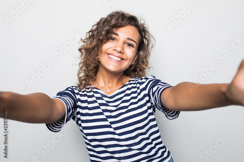 Close up portrait of a happy young curly woman making selfie against isolated white background