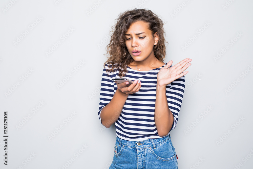 Cheerful curly woman smiling scream and talking on monbile phone isolated on gray background Cheerful curly woman smiling scream and talking on monbile phone isolated on gray background