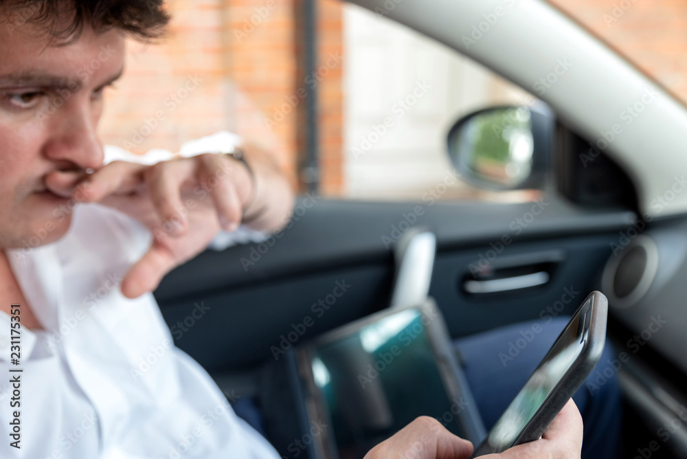 Businessman working on tablet and smartphone inside car on bright day Businessman working on tablet and smartphone inside car on bright day