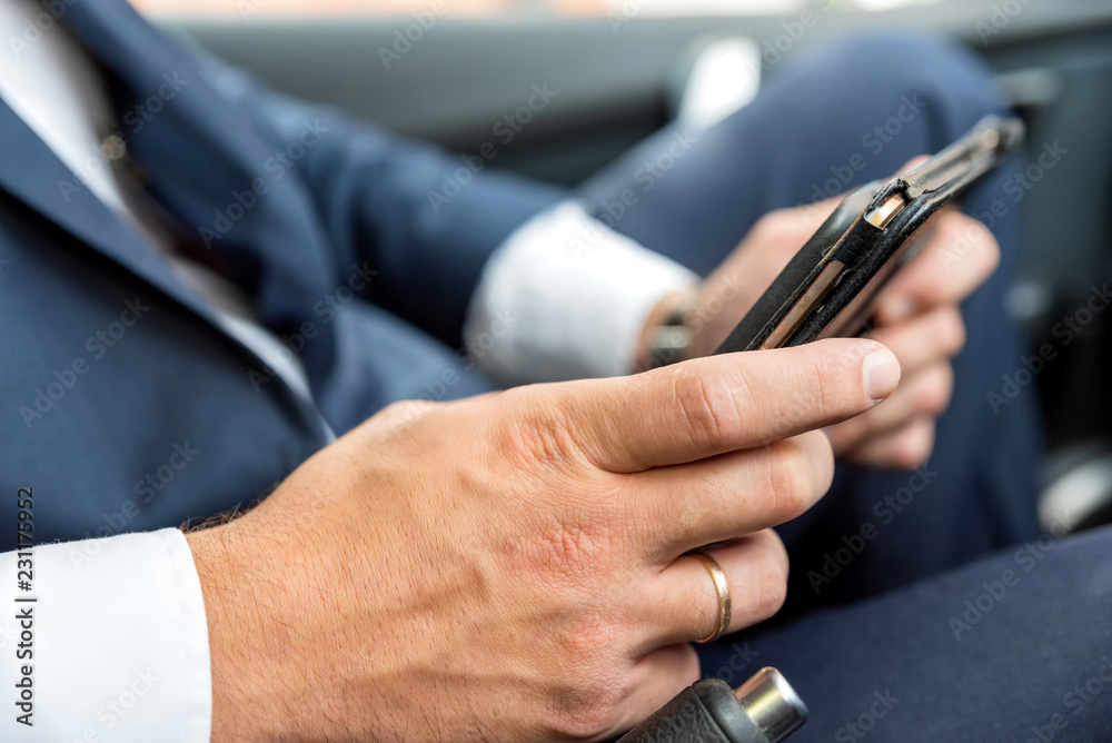 Businessman working on tablet and smartphone inside car on bright day Businessman working on tablet and smartphone inside car on bright day