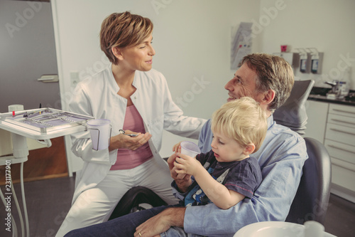 Wallpaper Mural Female dentist talking to patient with son sitting on his lap Torontodigital.ca