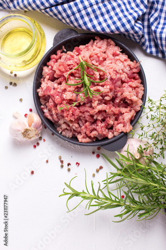 Raw minced meat in bowl with ingredients for cooking