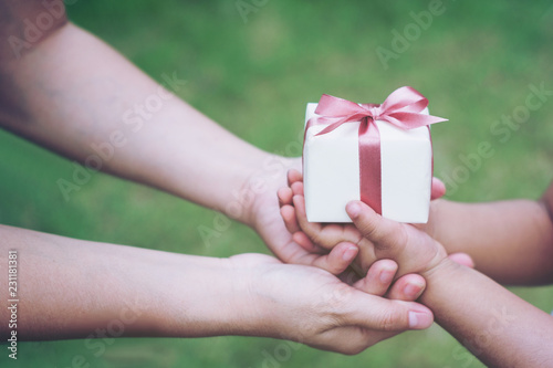 Fototapeta Naklejka Na Ścianę i Meble -  Holidays, present, christmas, Valentines day childhood and happiness concept - close up of  little girl and mother hands with gift box green background. selective focus.soft focus