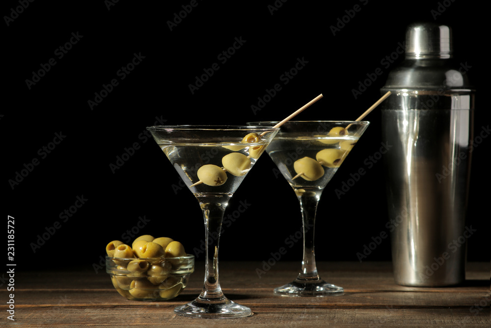 Martini in a glass wineglass with green olives on a skewer on a brown wooden table. cocktails. bar Martini in a glass wineglass with green olives on a skewer on a brown wooden table. cocktails. bar