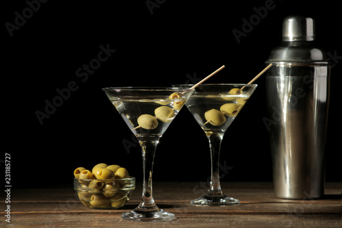 Martini in a glass wineglass with green olives on a skewer on a brown wooden table. cocktails. bar