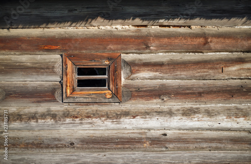 Small wood window in the wall of old wooden log house. Space for text.