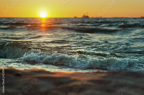 Sunset over the sea. Reflection of sunlight in the sea waves. Red and yellow sky in the rays of the sunset.