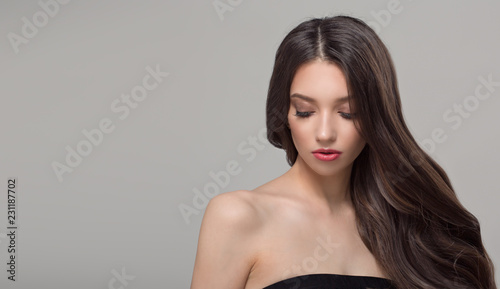 Portrait of a fashionable woman and long dark hair. Wavy shiny hair