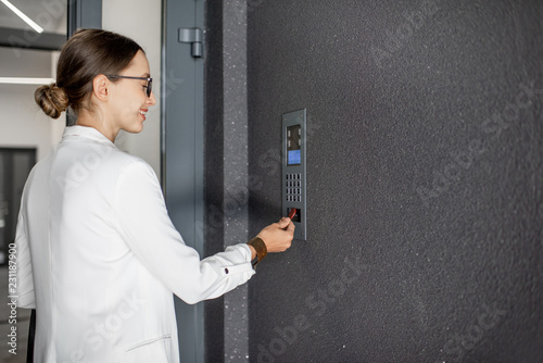 Konstfotografi Young business woman in white suit touching the intercom with keychain opening t