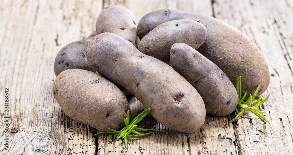 Vitolette noir or purple potato. On a wooden background. Vitolette noir or purple potato. On a wooden background.