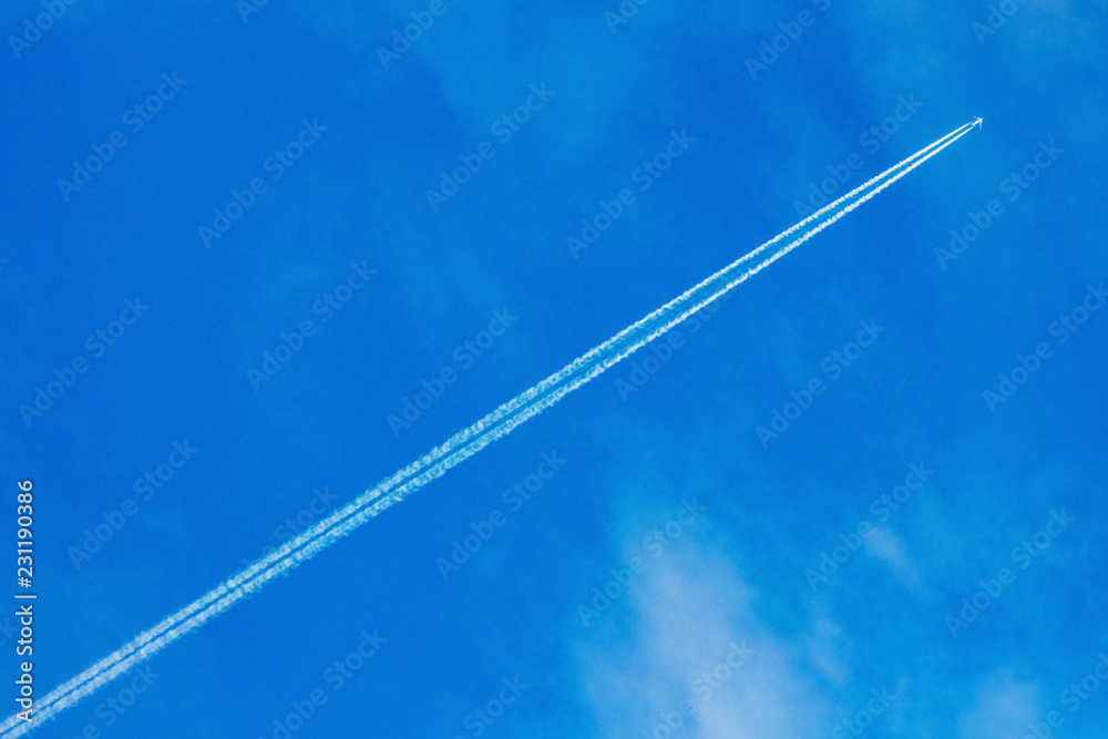 An airplane and a trail from an airplane in a blue sky_ An airplane and a trail from an airplane in a blue sky_