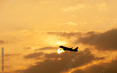 Silhouette of commercial airplane against beautiful orange sky at sunset