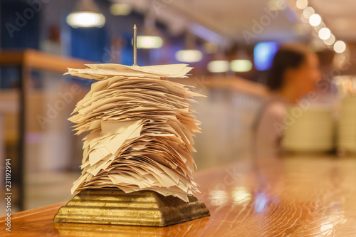 Checks from completed orders in the bar or restaurant kitchen impaled on a sharp thin iron needle on stand. Concept checker, stand for checks, checkbox