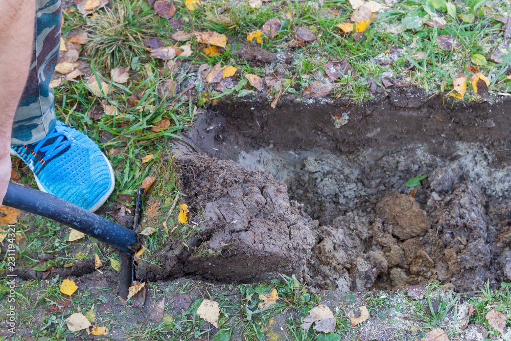 Fototapeta premium Man digging a ditch with a shovel in autumn