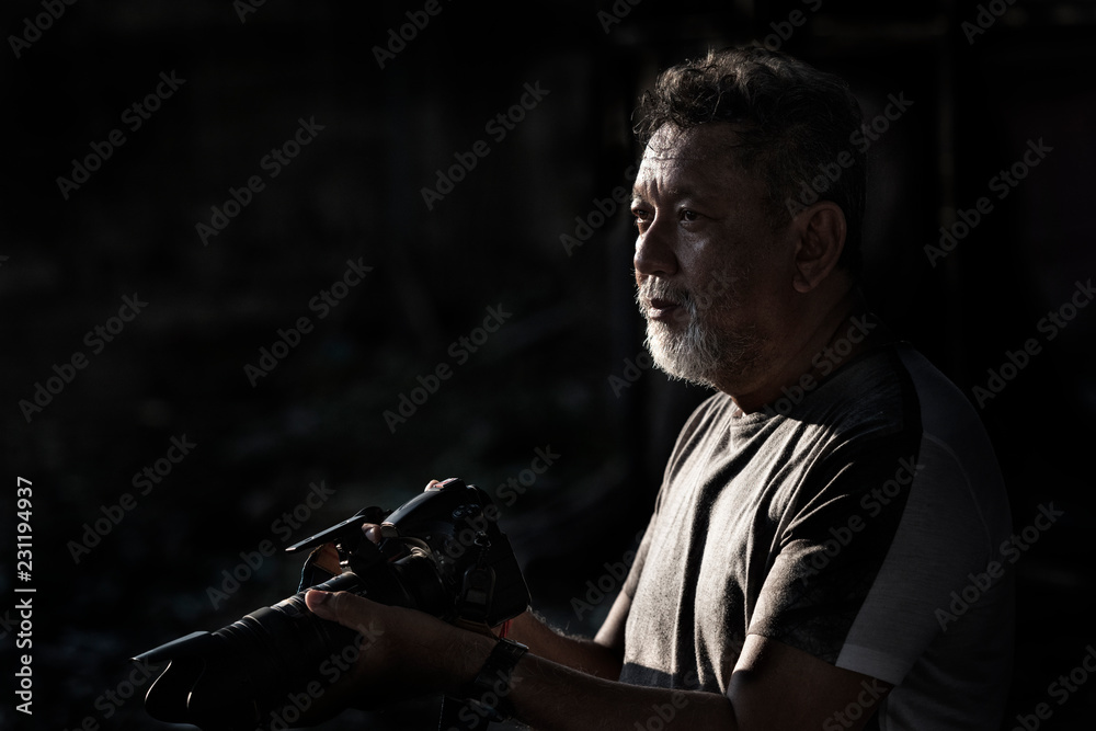 portrait asia Photographer men with camera in low key light on a black background. portrait asia Photographer men with camera in low key light on a black background.