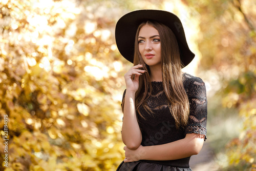 beautiful woman in black dress and hat in autumn