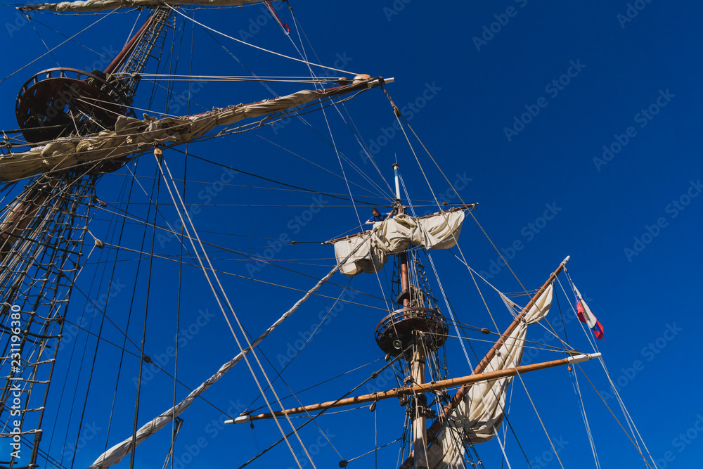Sailors work with sails at a height on a traditional sailboat