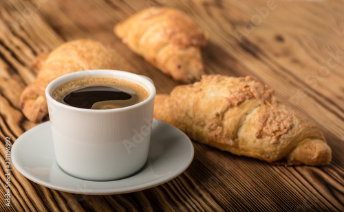 Cup of coffee with croissants on a wooden table