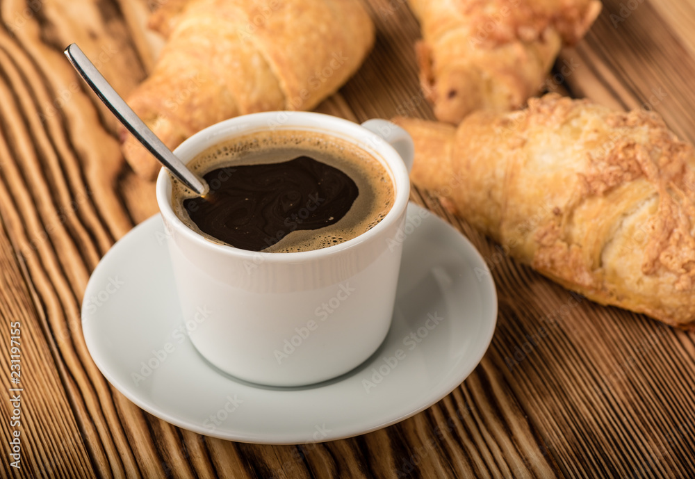 Cup of coffee with croissants on a wooden table Cup of coffee with croissants on a wooden table