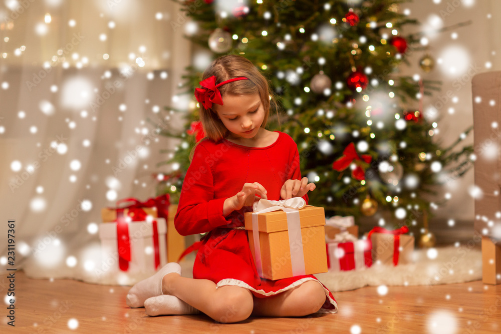 christmas, holidays and childhood concept - girl in red dress with gift box at home christmas, holidays and childhood concept - girl in red dress with gift box at home