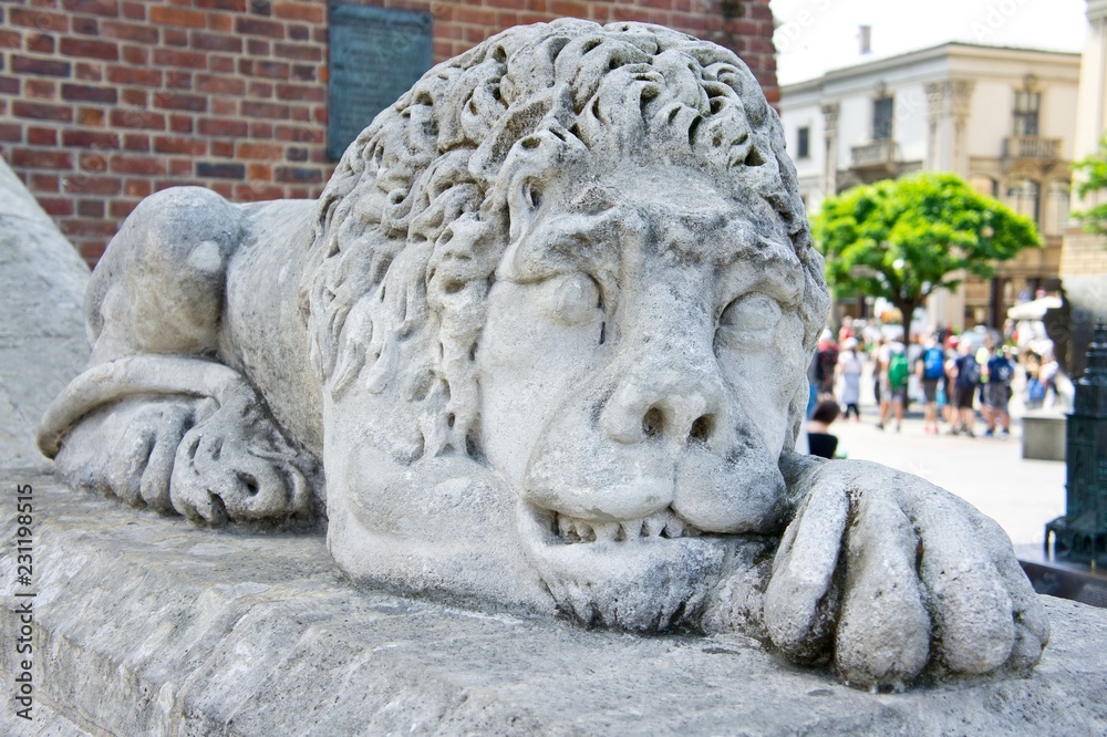 Stone sculpture of a lion lying in front of the entrance to an old building