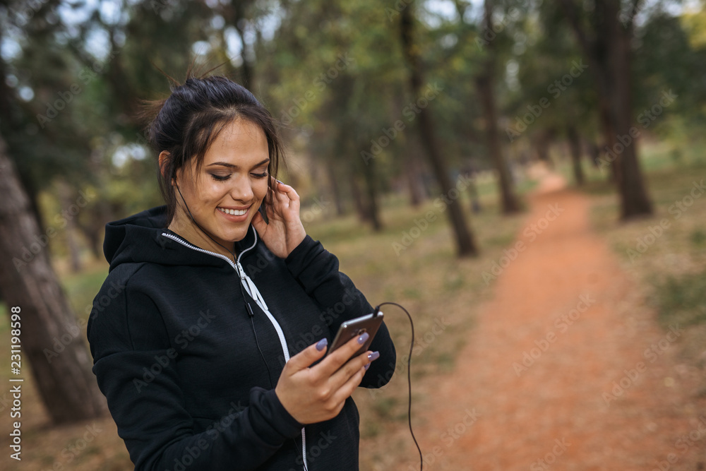 Setting up a playlist for her run in city park Setting up a playlist for her run in city park