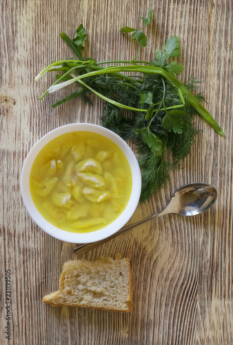 Breakfast, diet soup, bread, herbs, onions on a wooden table