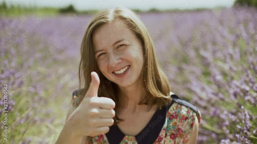 Young woman enjoying and smiling in a blooming lavender field in Provence, France. Close-up portrait. Girl smiling and thumb up Young woman enjoying and smiling in a blooming lavender field in Provence, France. Close-up portrait. Girl smiling and thumb up