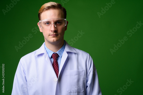 Young handsome man doctor with blond hair wearing protective gla