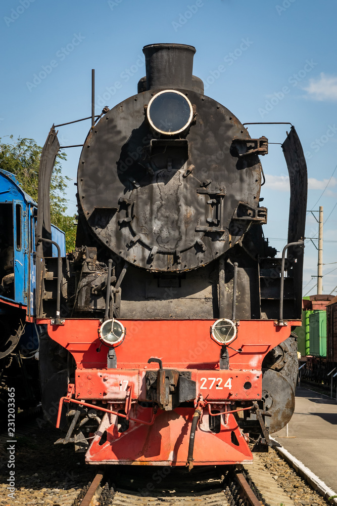 Naklejka premium Stara lokomotywa parowa obok peronu kolejowego. Pociąg retro.