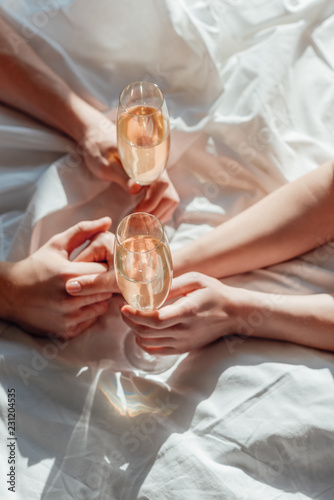 cropped shot of couple with glasses of champagne holding hands on ned