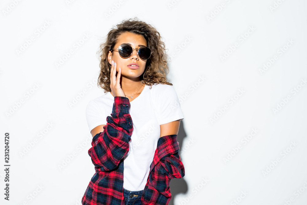 Portrait of curly beautiful latin woman in sunglasses and plaid shirt isolated on white background Portrait of curly beautiful latin woman in sunglasses and plaid shirt isolated on white background