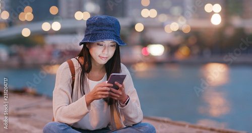Woman use of mobile phone beside the sea at night