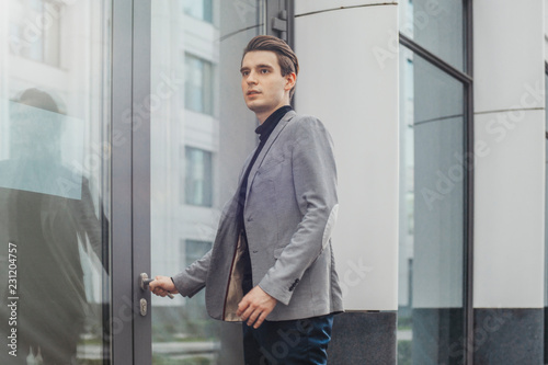 Close up of young business man opening door of modern business center.