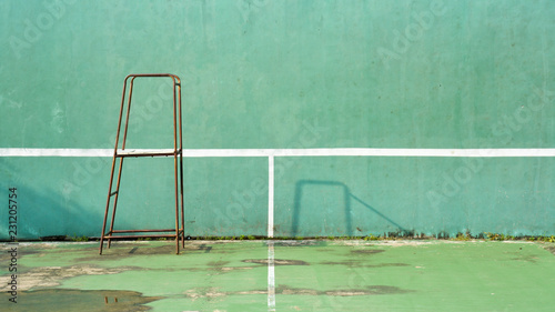 rusty committee chair with green tennis court for practice