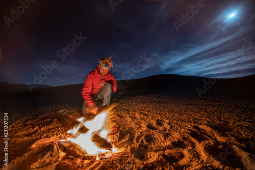 While looking for meteorites at Atacama Desert we made a stop for sleeping in the middle of the amazing Atacama Desert. One man on a camp fire under the full moon light on a starry night. Chile 
