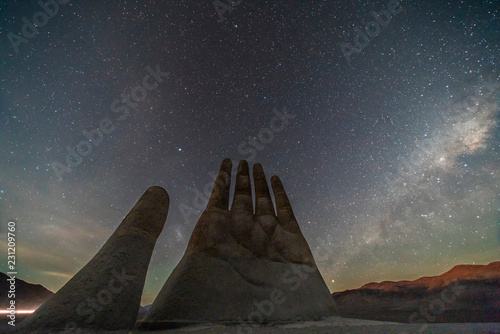 Fotografi The amazing Mano del Desierto (Desert Hand) with a Milky Way in the southern hemisphere and the Magellan Clouds galaxies with millions of stars around the night sky just amazing