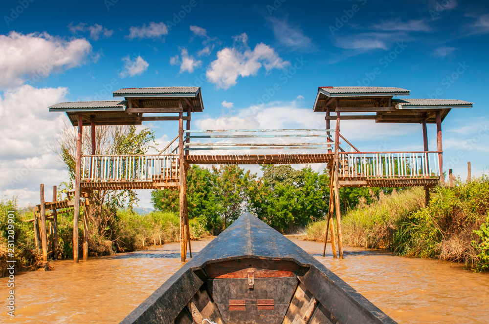 Wooden boat travels under wooden bridge on canal, Inle Lake, Shan State, Myanmar. Wooden boat travels under wooden bridge on canal, Inle Lake, Shan State, Myanmar.