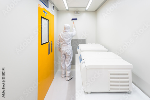 A scientist in sterile coverall gown using lint roller for cleaning laboratory. Cleanroom facility. photo