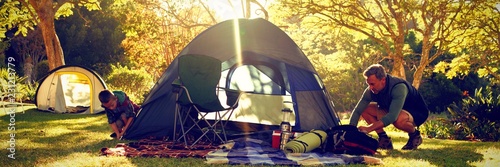 Billede på lærred Boy setting up the tent at campsite