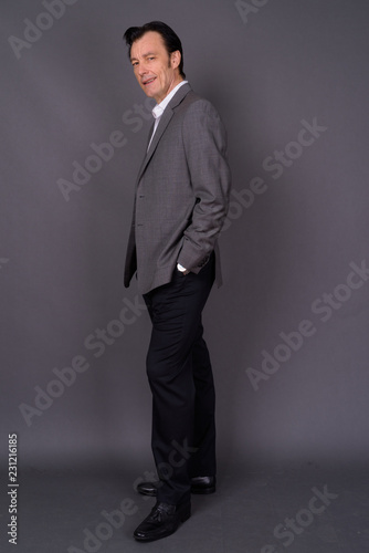 Portrait of mature handsome businessman against gray background