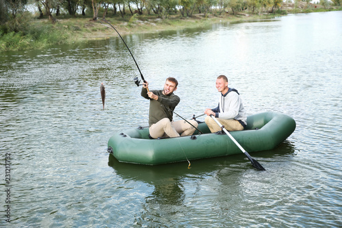 Friends fishing from boat on river. Recreational activity