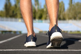 Sporty man running at stadium on sunny morning, focus on legs