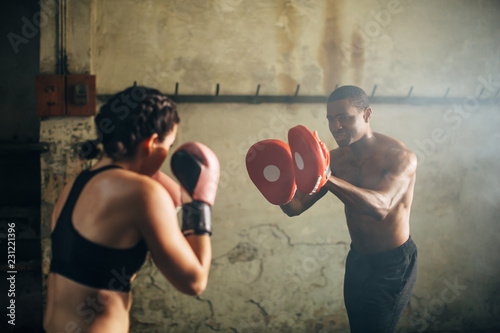 Strong brunette woman boxing indoors with her coach.
